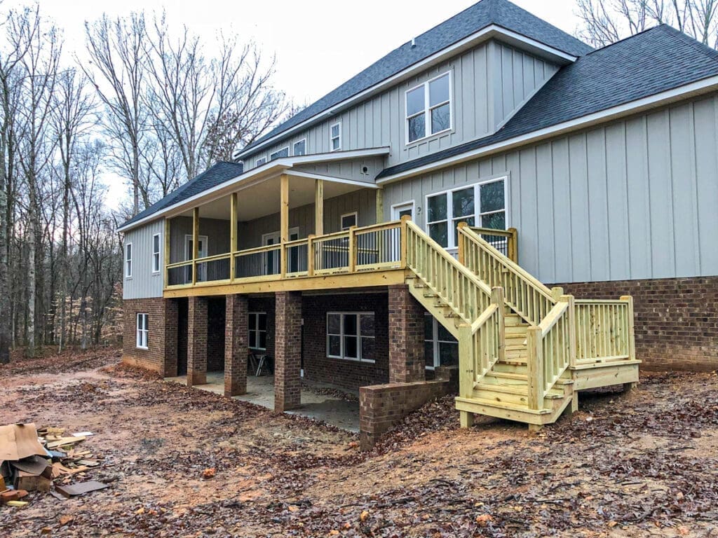 Newly constructed wooden deck and stairs attached to a house in a wooded area, showcasing outdoor living space enhancements by Home Deck and Fence Co. in Dickson County, Tennessee.