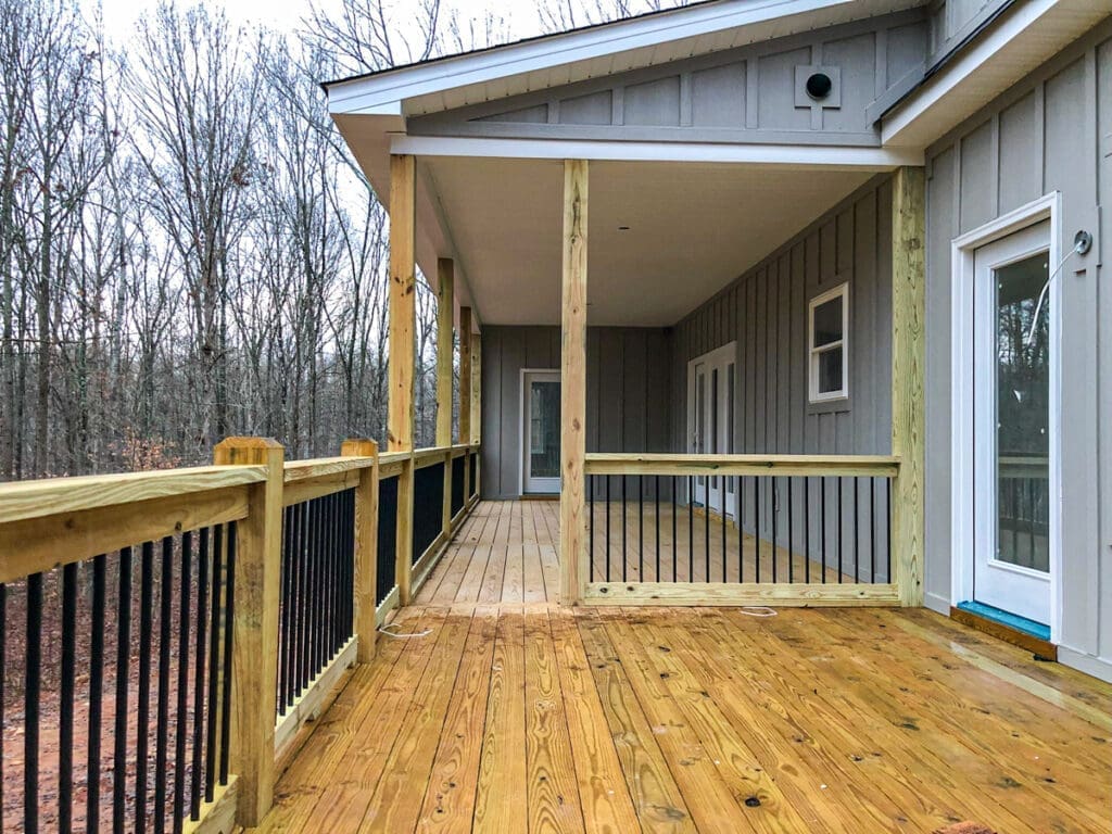 Newly constructed wooden deck with black railing, surrounded by trees, showcasing outdoor living space in Middle Tennessee.