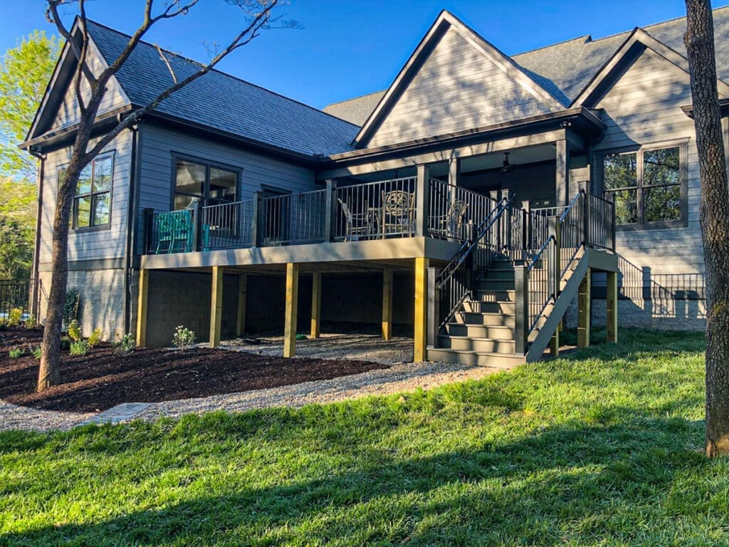 Modern home deck with black railing and stairs, surrounded by landscaped grass and trees, showcasing outdoor living space in Dickson County, Tennessee.
