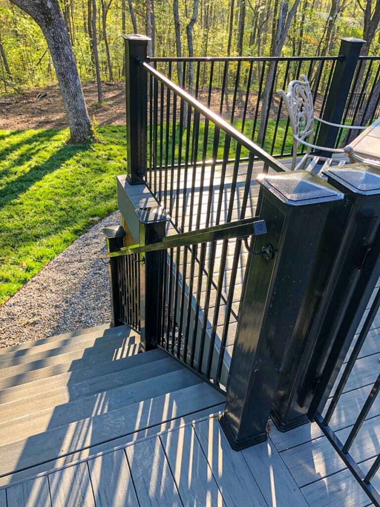 Deck stairs with black railing leading to a grassy area, showcasing outdoor structure and design by Home Deck and Fence Co. in Middle Tennessee.