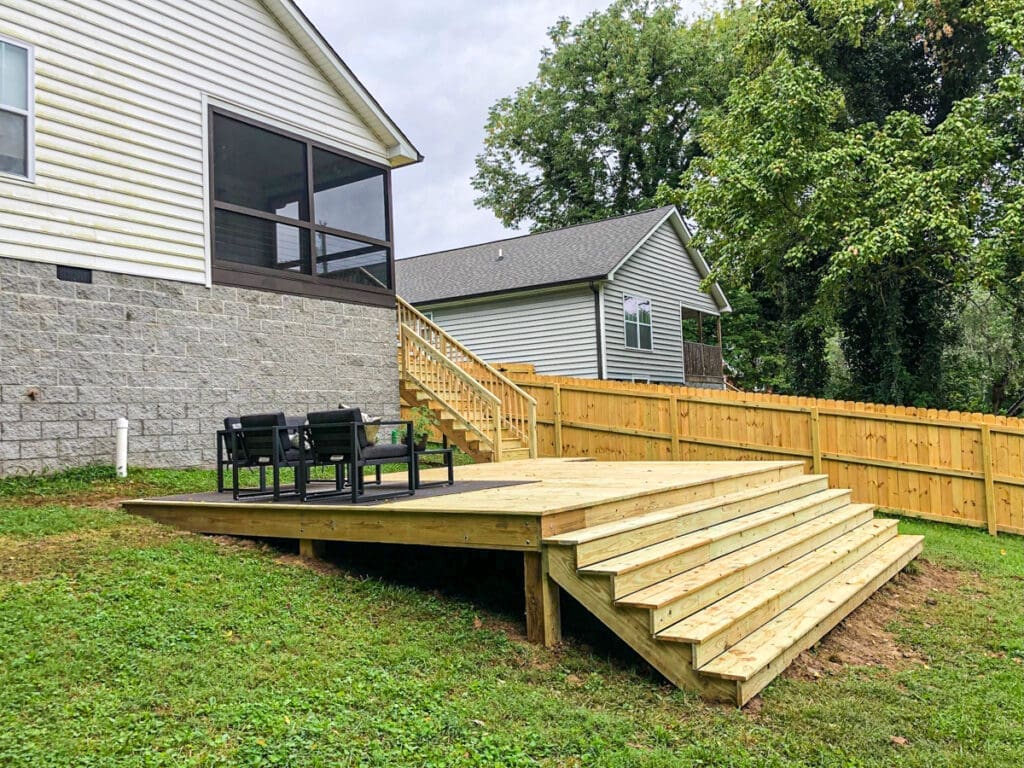 Backyard deck with steps, black chairs, and wooden privacy fence in Middle Tennessee, showcasing professional craftsmanship by Home Deck & Fence.