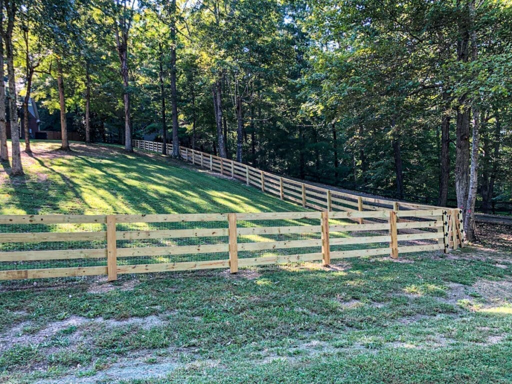 Wooden fenced yard in Middle Tennessee, showcasing pet-friendly fencing solution, surrounded by trees and grassy area.