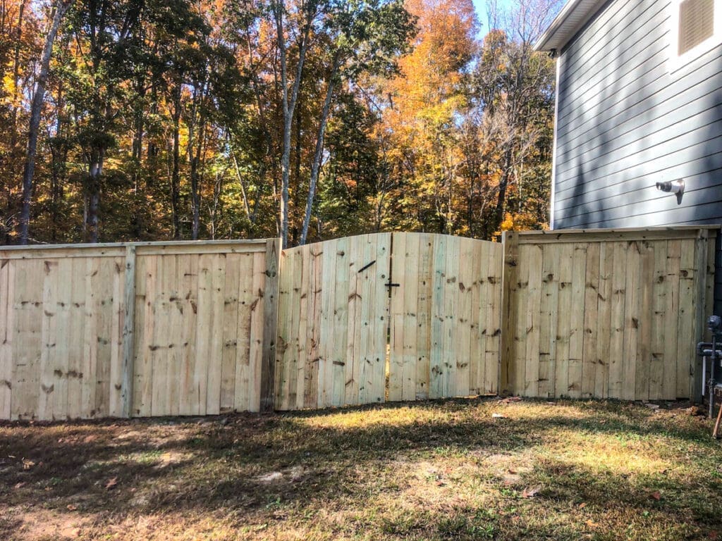 New wooden fence with archway gate, surrounded by autumn foliage, showcasing a secure and stylish outdoor structure for privacy in Middle Tennessee.