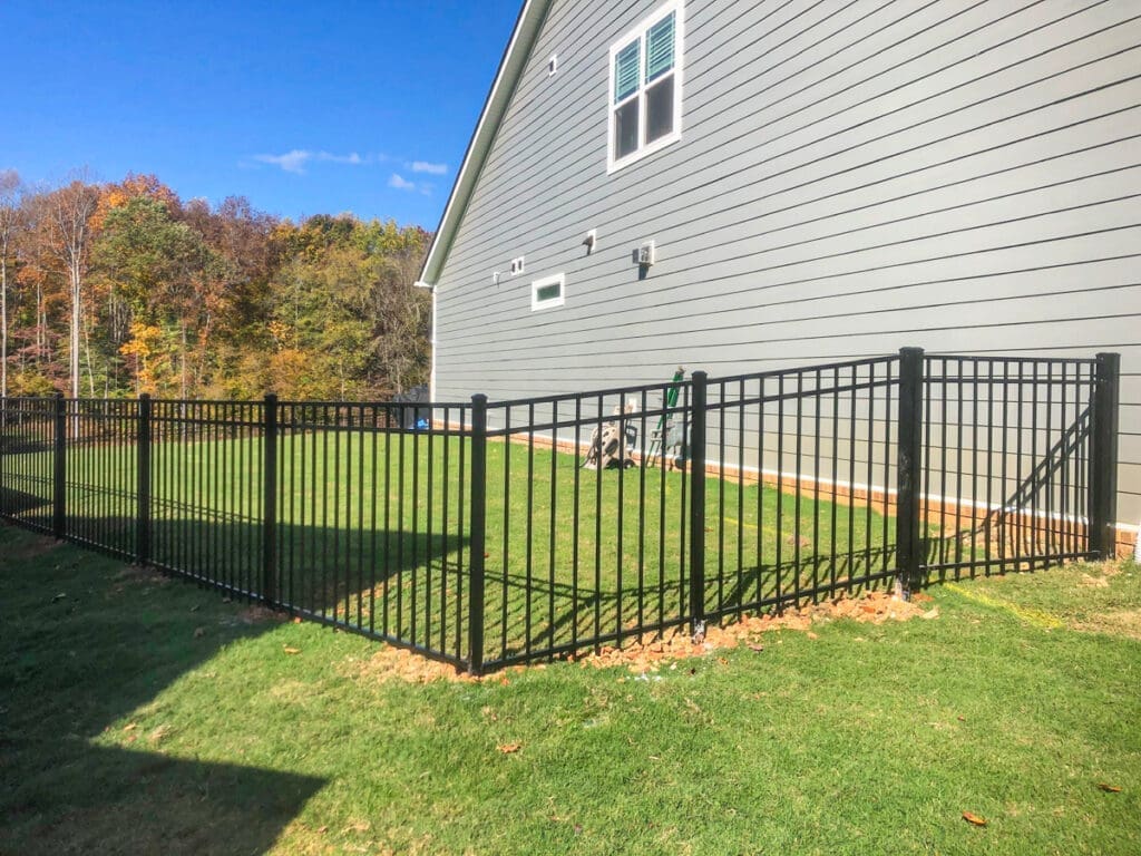 Pet-friendly black aluminum fence enclosing a grassy backyard, adjacent to a modern home in Middle Tennessee.