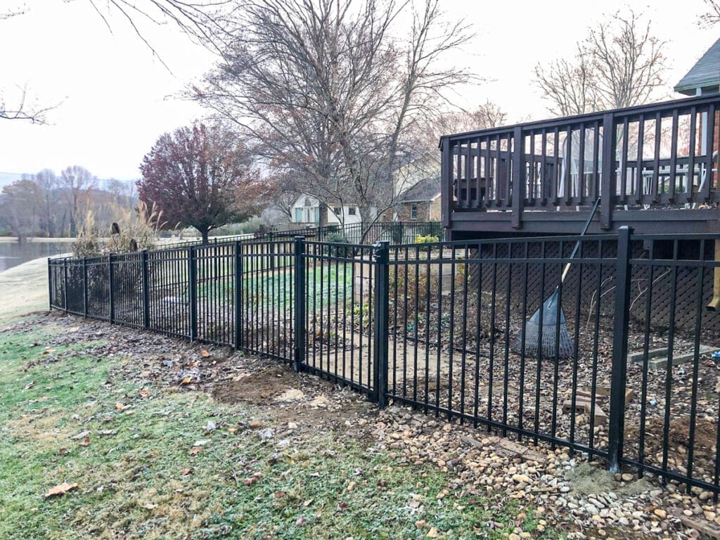 Black metal fence enclosing a landscaped yard with a deck in Middle Tennessee, showcasing professional fence installation by Home Deck & Fence.
