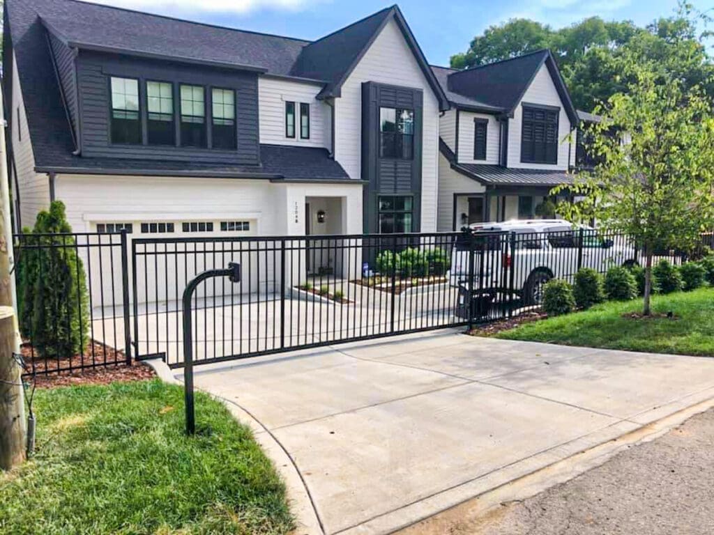 Modern home exterior with a black metal fence and driveway, showcasing professional fence installation in Middle Tennessee, emphasizing quality and aesthetics.