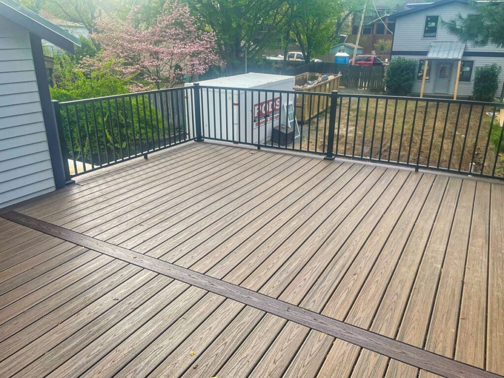 Decking installation with wooden planks and black railing in a residential outdoor space, showcasing safety and style for homeowners in Dickson, TN.