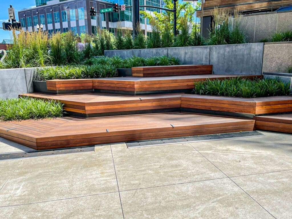 Wooden deck steps with green landscaping in an urban outdoor space, showcasing modern design for enhancing outdoor areas.