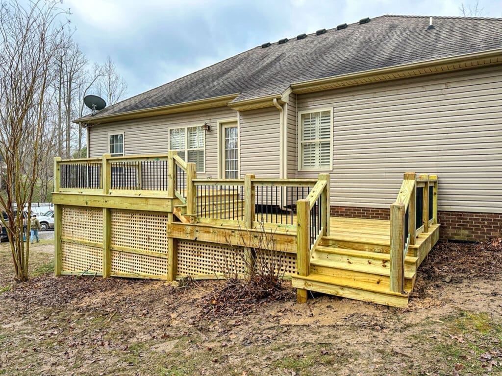 Custom wooden deck with railings and stairs, situated at the back of a home in Dickson County, showcasing outdoor living space for homeowners in Middle Tennessee.