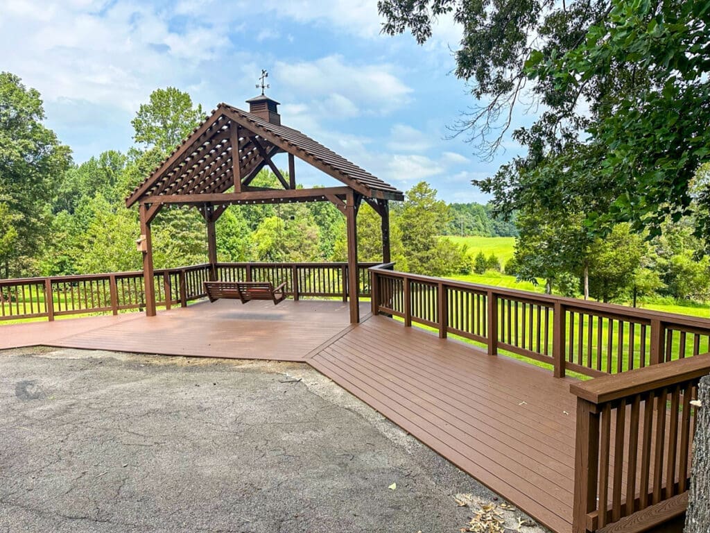 Custom wooden deck and gazebo with swing, surrounded by greenery in Middle Tennessee, showcasing outdoor living space enhancements by Home Deck and Fence Co.