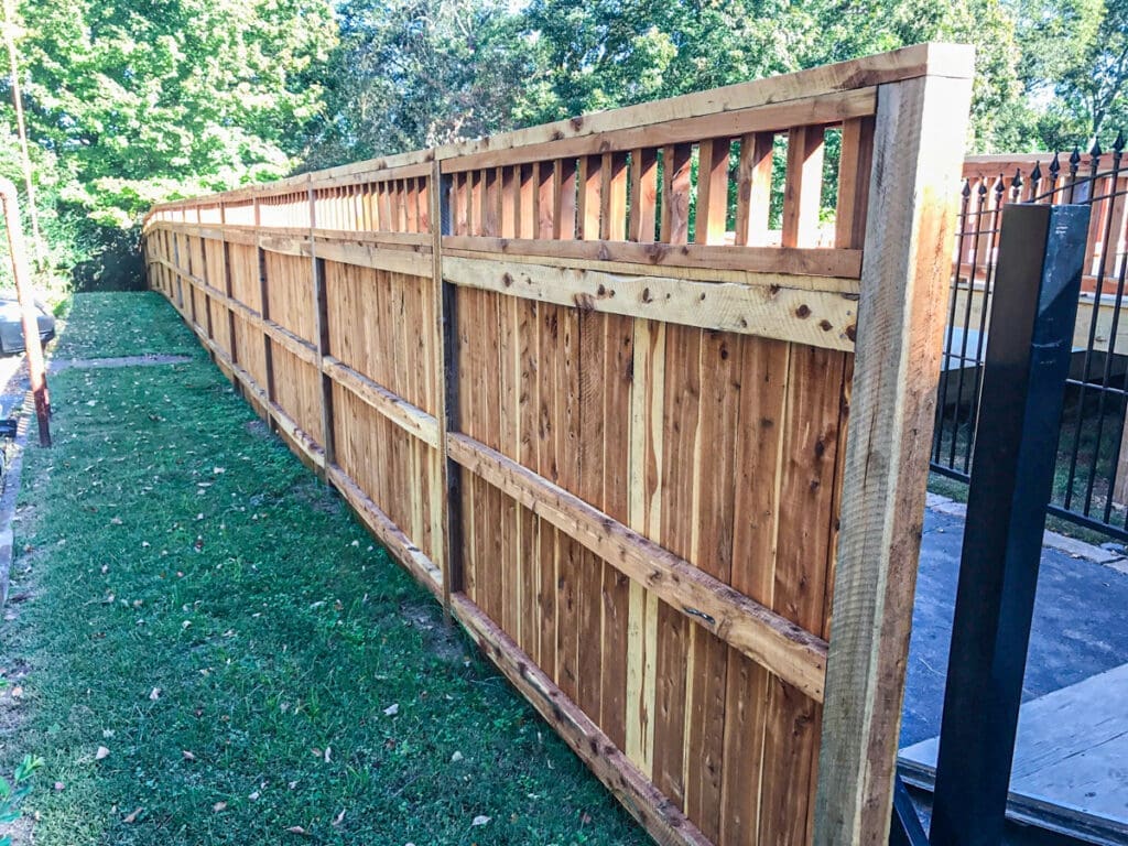 Wooden privacy fence installation in a landscaped yard, showcasing craftsmanship and design, relevant to fencing services by Home Deck & Fence Co. in Middle Tennessee.