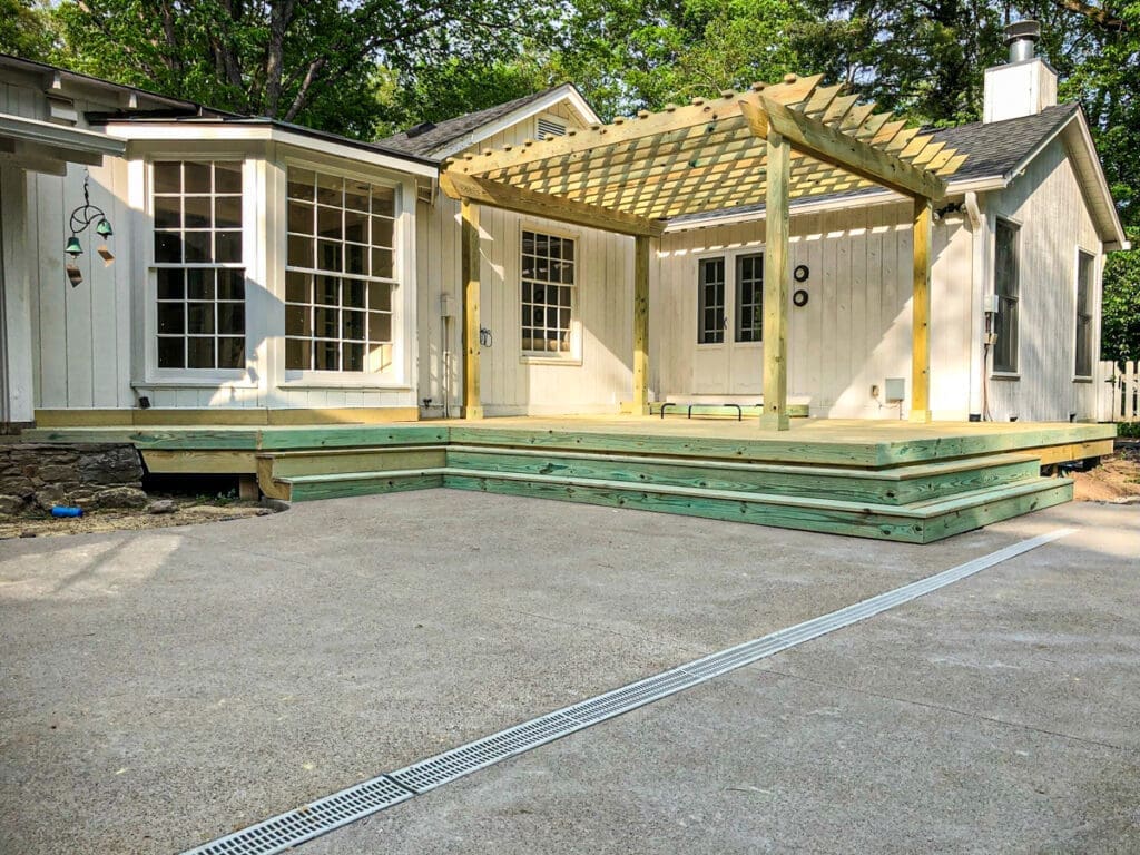 Custom wooden deck with pergola attached to a house, showcasing outdoor living space in Middle Tennessee.