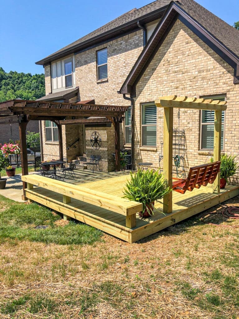 Custom wooden deck with swing and pergola in backyard of a home in Dickson County, Tennessee, showcasing outdoor living space for entertaining and relaxation.