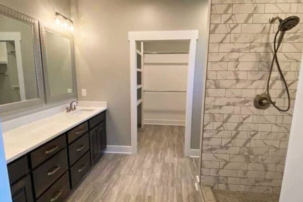 Modern bathroom design featuring a double vanity with dark cabinetry, a large mirror, and a spacious walk-in shower with tiled walls, showcasing quality craftsmanship by HDF Builders in Middle Tennessee.