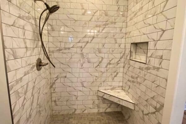 Modern shower design featuring marble tile walls, a wall-mounted showerhead, and a built-in bench, highlighting custom home features by HDF Builders in Middle Tennessee.