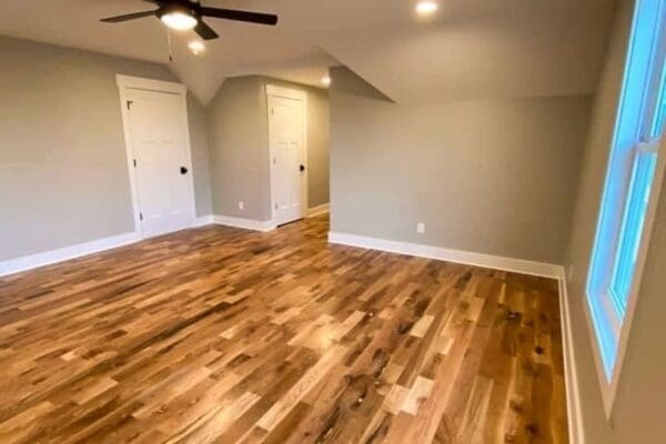 Empty room featuring hardwood flooring, light gray walls, ceiling fan, and two white doors, showcasing a modern custom home interior by HDF Builders in Middle Tennessee.
