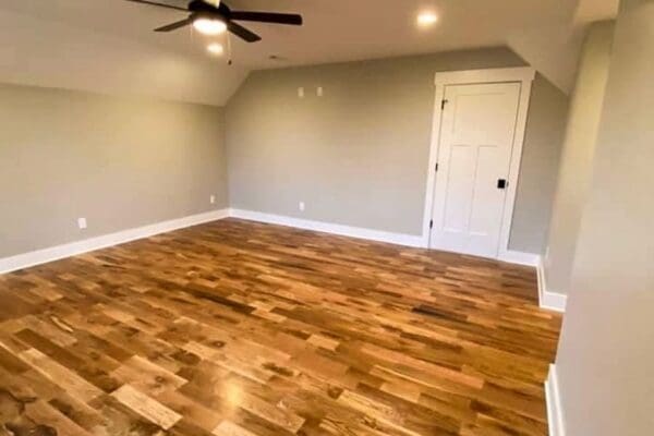 Spacious interior of a custom-built room featuring hardwood flooring, gray walls, ceiling fan, and a white door, reflecting modern design elements from HDF Builders in Middle Tennessee.