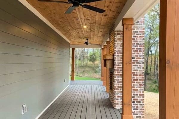 Covered porch of a custom home by HDF Builders featuring wooden ceiling, ceiling fan, and brick accents, leading to a scenic outdoor view in Middle Tennessee.