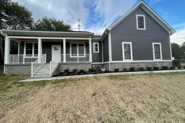 Modern custom home exterior featuring gray siding, covered front porch, landscaped yard, and stone accents in Middle Tennessee.