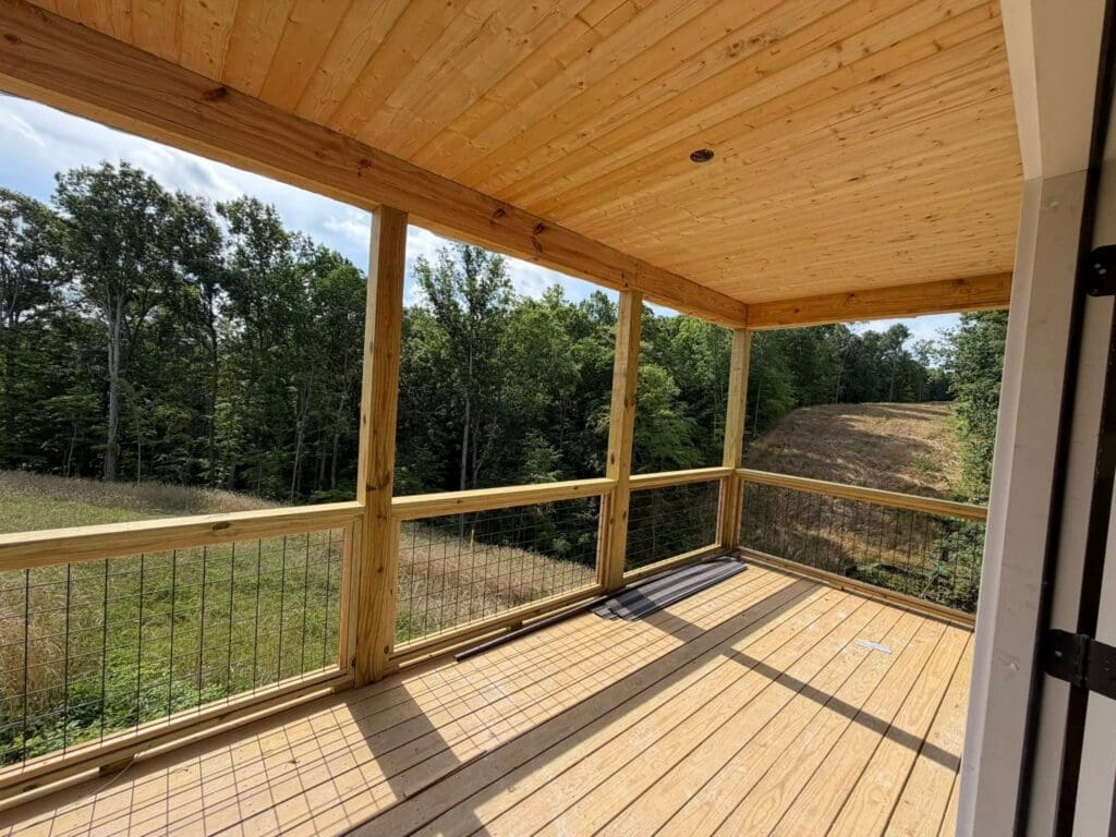 Spacious covered deck with tongue-and-groove wood ceiling, pressure-treated decking, and open Wild Hog railings designed for luxury outdoor living in Middle Tennessee